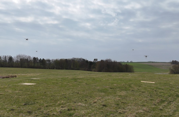 Několik DRONů letí současně nad travnatým polem při testu